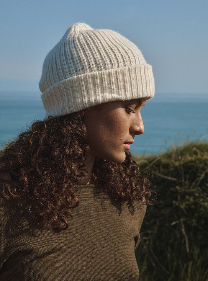 Vue de côté du bonnet ambre blanc naturel avec un pull col v en laine