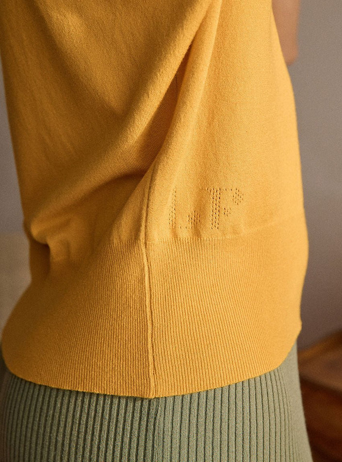 Détail de la signature et de la finition bord-côte sur le polo Delphine jaune d'or